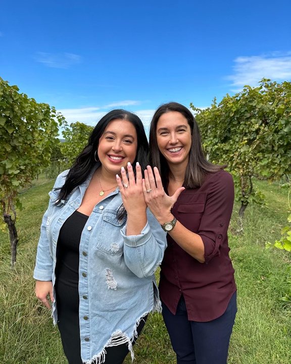 beautiful engaged couple in an orchard showing their engagement rings